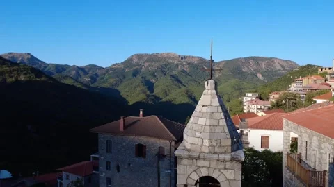 Rotating View of Stone Bell Tower with Cross beside High Mountain at Sunrise Stock Footage 326353696
