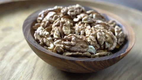 Rotating walnuts in a shell in a wooden bowl on a wooden background Stock Footage 229414276