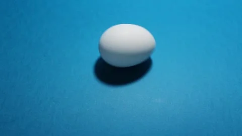 Rotating white chicken boiled egg on blue table Stock Footage 270414863