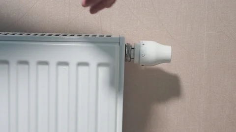Rotating white temperature valve with hand on wall mounted heating water 库存影片 124723258
