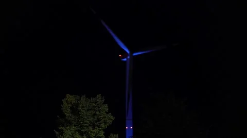 A rotating wind turbine at night with blue light Video stock 203855893