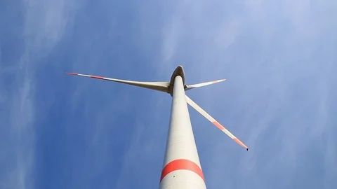 Rotating wind turbine propeller blades in the blue sky - view from the ground Stock Footage 75545941
