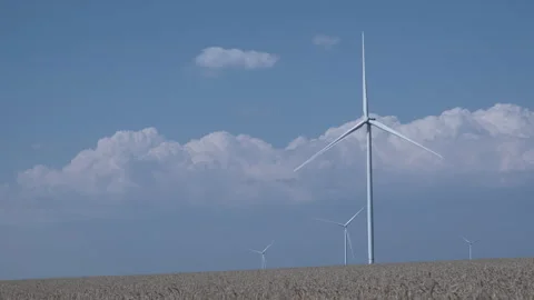 Rotating wind turbines in a field of wheat against the blue sky Stock Footage 246084398