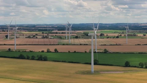 Rotating Wind Turbines Generate Electricity in the Expansive Farmland of Stock Footage 341838163