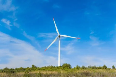 Rotating windmill generating renewable energy wind power at land. Sustainabil Foto stock