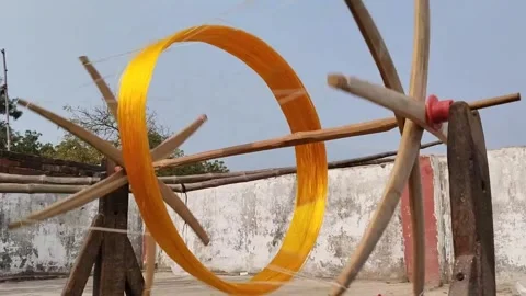 Rotating a wooden spindle to extract small silk strands from yellow silk coc Stock Footage 234933464