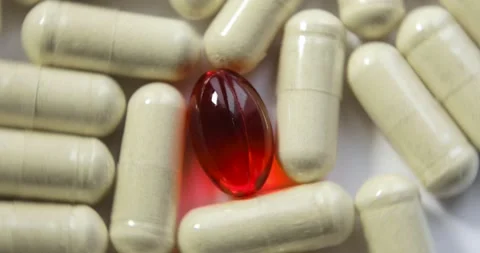 Rotating yellow pills and red gel capsule on white background, closeup view. Vídeo Stock 145446552