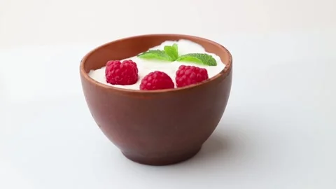 Rotating of yogurt with raspberry in clay cups. Side view. Stock Footage 136050739