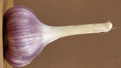 Rotating young garlic on brown background. Vertical screen Stock Footage 247712719