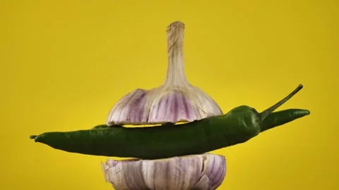 Rotating young garlic with hot pepper inside on a yellow background. Stock Footage 248086226