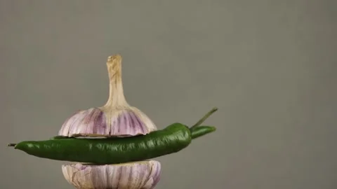 Rotating young garlic with hot pepper inside on a gray background.Copy space Stock Footage 248086706