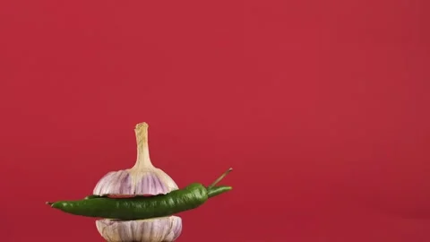 Rotating young garlic with hot pepper inside on a red background.Copy space Stock Footage 248363662