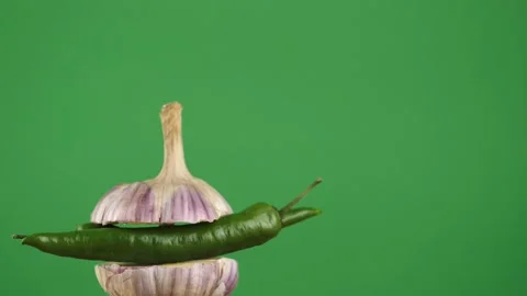 Rotating young garlic with hot pepper inside on a green background.Copy space Stock Footage 248501763