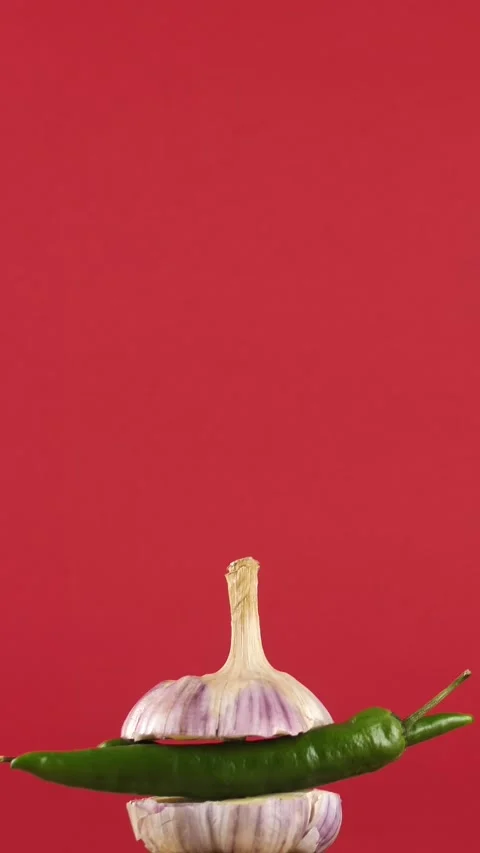 Rotating young garlic with hot pepper inside on a checkered background. Young Stock Footage 308045159