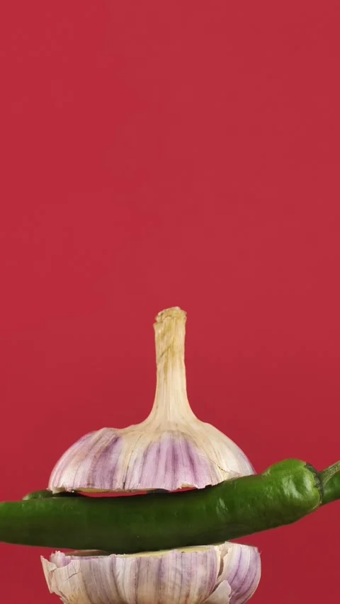 Rotating young garlic with hot pepper inside on a checkered background. Young Stock Footage 308205786