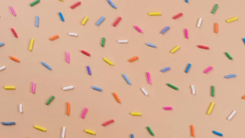 A rotation background of sprinkles for sweets on a beige background.The concept Stock Footage 196243394