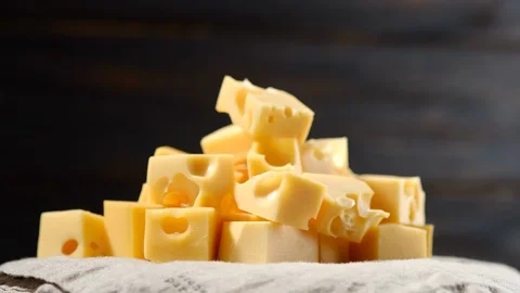 Rotation chopped of cube hard cheese on dark wooden background Stock-Footage 129536775