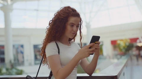 Rotation close up view of good looking curly ginger young woman using smartphone Stock Footage 114248370