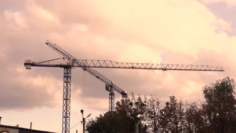 Rotation of a construction crane against the backdrop of a sunset sky with Stock Footage 143133321