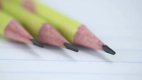 Rotation of graphite pencils on an empty sheet of open notebook in ruler. macro. Stock Footage 252241616