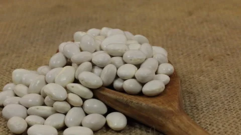 Rotation, heap of haricot beans falling from a wooden spoon on burlap. Stock Footage 87251510