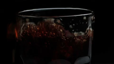 Rotation macro shot  of Cola Bubbles and Ice Cubes in a Glass. 動画素材 141808220