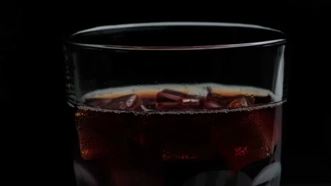Rotation macro shot  of Cola Bubbles and Ice Cubes in a Glass. Stock Footage 141809386