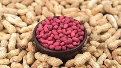Rotation of peeled peanuts in clay cup against background of unpeeled peanuts. Stock Footage 223265344