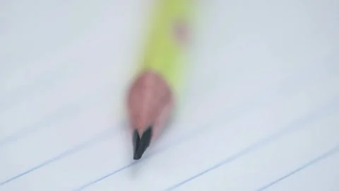 Rotation of sharpened graphite pencil in closeup on sheet of notebook in ruler Stock Footage 248153091