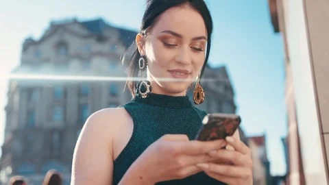 Rotation view of a beautiful brunette using her phone, happily smiling to the Stock Footage 76728217
