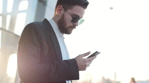 Rotation view of stylish man standing by the airport terminal and using phone Stock Footage 74863696