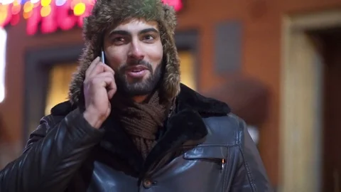 Rotation view of young smiling man talking via his phone. Winter season, cold Stock Footage 84652755