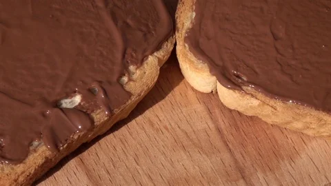 Rotation of white bread slices with chocolate paste on wood background close up. Stock Footage 99850707