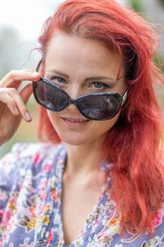 Rothaarige attraktivek junge Frau mit Sonnenbrille als Model posiert im Fr... Stock Photos