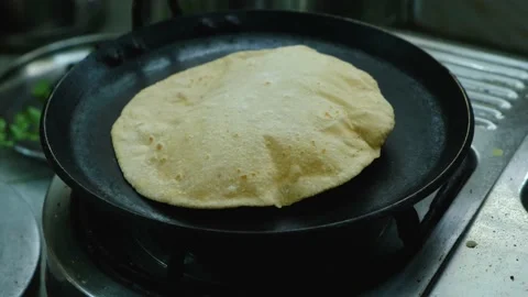 Roti ( Chapati , an Indian bread ) is being roasted on a hot pan. Stock Footage 161946569
