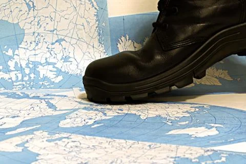 Rough black boot on world map Stock Photos