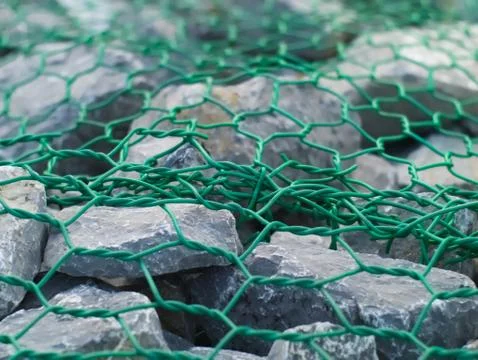 Rough bluish grey stone texture with green chain wire Stock Photos