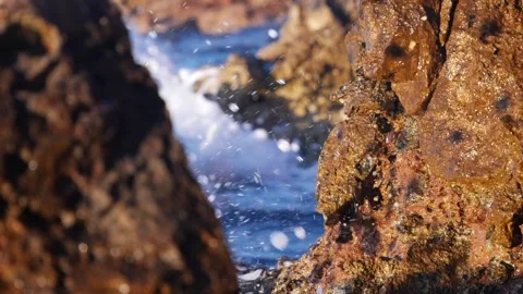 Rough brown rocks frame ocean water splashing into white foam. Stock Footage 337405838