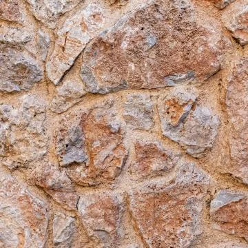 Rough brown stone wall close up, seamless textured background Foto stock