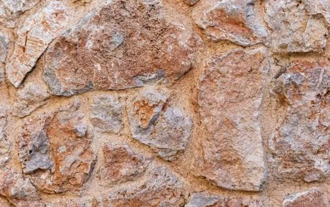 Rough brown stone wall close up, seamless textured background Stock Photos