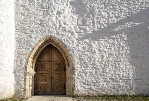 Rough, bumpy and uneven white wall and heavy Gothic wooden door at the entrance Stockfoto's