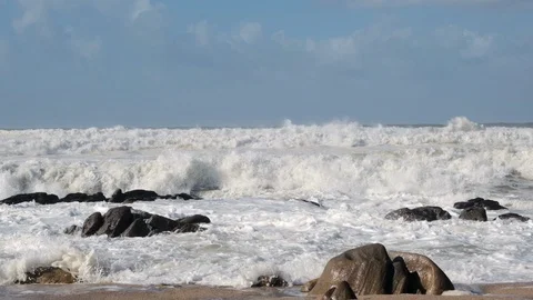 Rough, choppy white waves breaking against rocks on beach in slow motion Stock Footage 119294802
