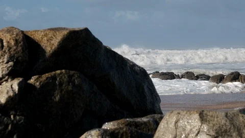 Rough, choppy white waves on ocean in winter, viewed from behind rocks Stock Footage 119295459