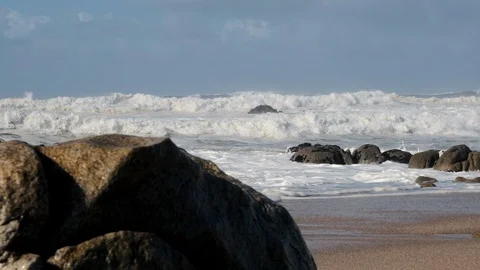 Rough, choppy white waves on ocean, reveal shot rising from behind rocks Stock Footage 119295562