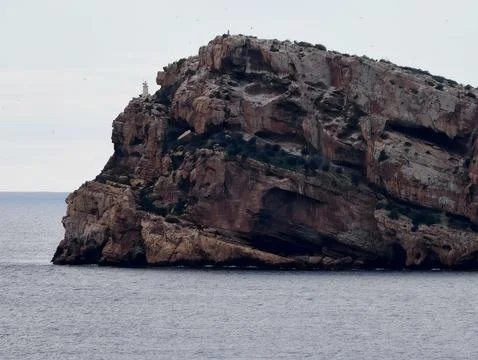 Rough cliffs meet tranquil waters, Jagged cliffs intersect smooth water with Stock Photos