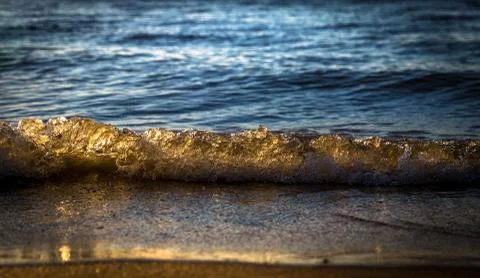 Rough colored ocean wave falling down at sunset time Stock Photos