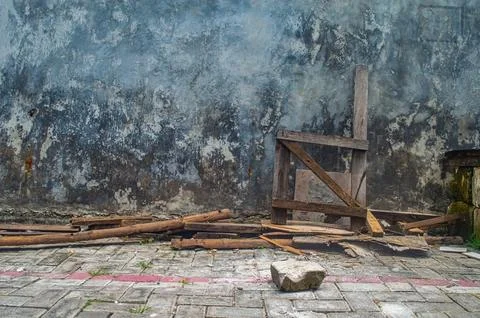Rough concrete wall with peeling paint and a scattering of broken wooden pl.. Stock Photos