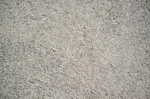 Rough concrete wall texture with small, grey rocks embedded in surface Stock Photos