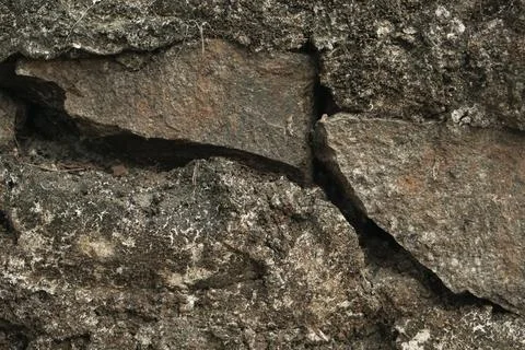 Rough dark stone wall texture with weathered rock surface Fotos de archivo