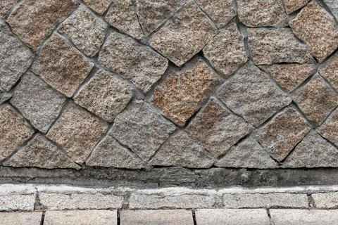 Rough granite cobblestone wall with diagonal block pattern Stock Photos